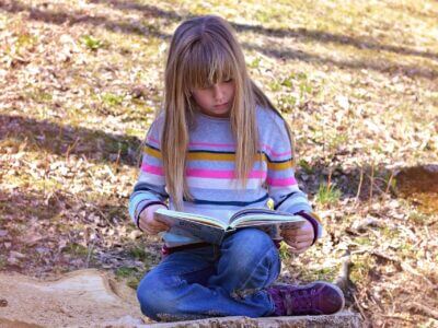 Mädchen liest ein Buch in der Natur - Lesepicknick