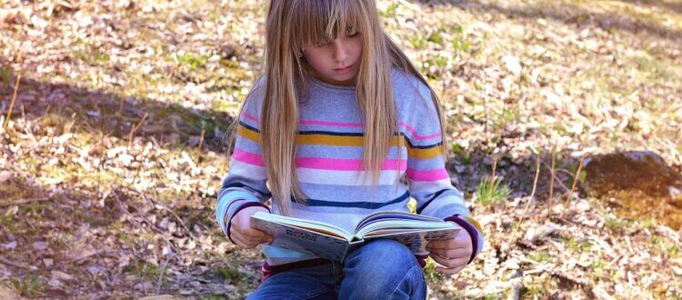 Mädchen liest ein Buch in der Natur - Lesepicknick